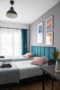 two beds in a bedroom with a blue headboard at ADLER Studio in Łódź