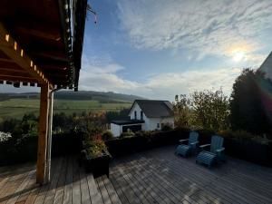 a deck with two blue chairs and a house at Eden Escapes in Olsberg