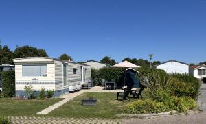 an rv parked in a yard with an umbrella at Camping de Zandput - ZP 340 in Vrouwenpolder