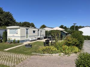 a mobile home with a yard with a patio at Camping de Zandput - ZP 340 in Vrouwenpolder +8 photos