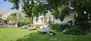 蒙塔古Montagu Vines Guesthouse的院子里摆放着躺椅，草地上趴着狗。