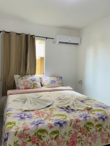 een slaapkamer met een bed met een bloemdekbed en een raam bij Ap na Barra dos Coqueiros in Barra dos Coqueiros