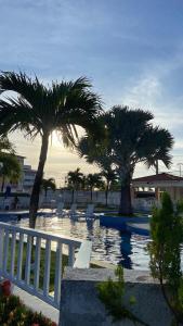 een zwembad met palmbomen naast een wit hek bij Ap na Barra dos Coqueiros in Barra dos Coqueiros