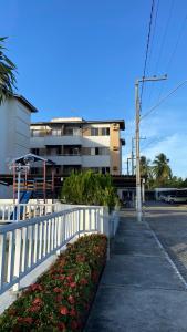 een wit hek voor een gebouw met bloemen bij Ap na Barra dos Coqueiros in Barra dos Coqueiros