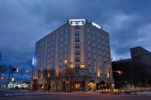 um edifício alto com um sinal em cima em Dormy Inn Express Koriyama em Koriyama