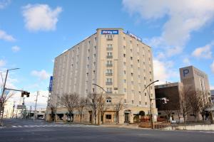 a large white building on the corner of a street at Dormy Inn Express Koriyama in Koriyama