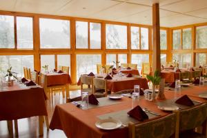 Dragon Nest Resort في Wangdiphodrang: غرفة طعام مع طاولات وكراسي ونوافذ
