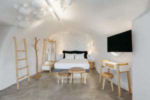 a bedroom with a bed and a table and chairs at Theano Cave Suites & Villas in Imerovigli