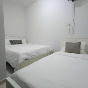 2 bedden in een witte kamer met witte lakens bij Melaka Kota Home in Melaka