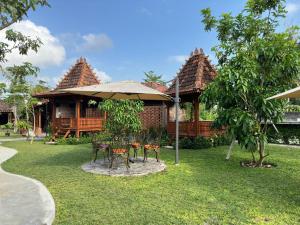 a table and chairs under an umbrella in a yard at Nglaras Resort Yogyakarta in Ngaglik