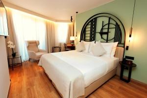 a bedroom with a large white bed and a chair at Zeus Essence Bucharest Opera in Bucharest