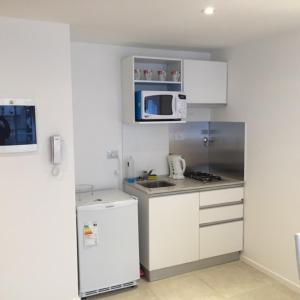 una pequeña cocina con armarios blancos y microondas en Casa ivana 3 en Buenos Aires