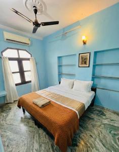 a bed in a blue room with a ceiling fan at Hotel Poonam Pushkar in Pushkar