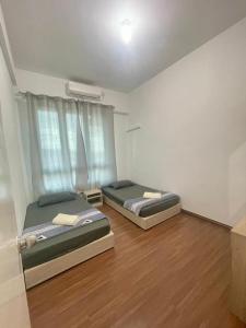twee bedden in een kamer met houten vloeren bij Jhomestay1 in Sandakan +10 foto's