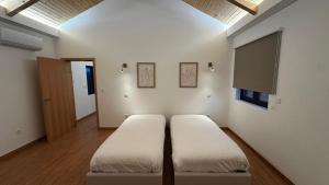 due letti in una stanza con pareti bianche e una finestra di Quinta do Codeçal a Vila Real