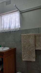 een badkamer met een wastafel en een raam bij 'The Cape Robin' studio apartment in Hoheizen +20 foto's