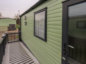 a green house with a porch and a window at Foxwood Hideaway in Carnforth