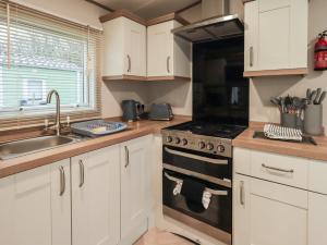 a kitchen with white cabinets and a stove top oven at Foxwood Hideaway in Carnforth
