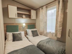 two beds in a small room with a window at Foxwood Hideaway in Carnforth