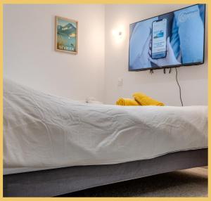 a white couch with a tv on a wall at L'Ecrin du Lac I Studio I Sévrier in Sévrier