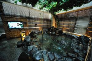 a hot tub in a room with rocks and a tv at Dormy Inn Express Koriyama in Koriyama