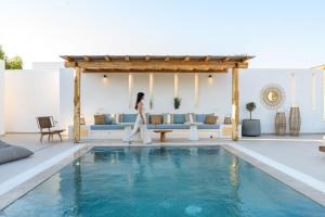 a woman is standing next to a swimming pool at Noble Pearl Villas Paros in Santa Maria