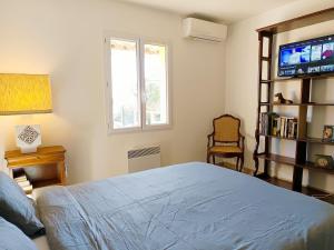 Un dormitorio con una cama, un televisor y una silla. en Face à la Citadelle - Jardin & Parking privé, en Forcalquier