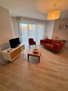 a living room with a couch and a table at Domitys Les Châtaigniers in Panazol