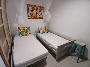 two beds in a small room with a painting on the wall at Superbe T3 avec une grande terrasse et un accès direct aux 2 plages Gros Raisin in Sainte-Luce +7 photos