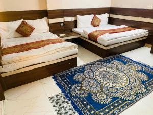 two beds in a room with a blue and white rug at Hotel Churu Palace in Jaipur