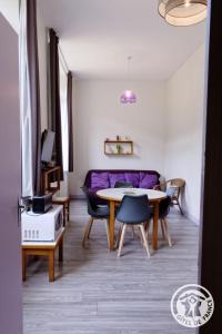 a living room with a table and a purple couch at Gite ecole in Soursac