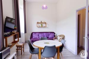 a living room with a table and purple couch at Gite ecole in Soursac