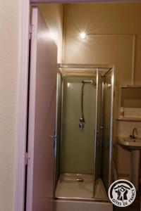 a shower with a glass door in a bathroom at Gite ecole in Soursac +6 photos