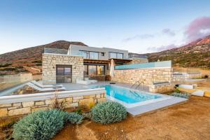 a house with a swimming pool in front of a mountain at Anemelia Villas in Karpathos