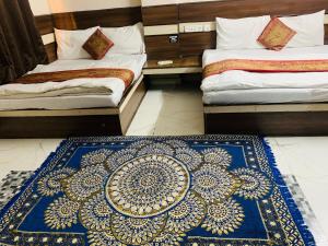 a bedroom with two beds and a blue and white rug at Hotel Churu Palace in Jaipur