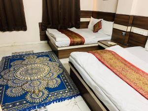a room with two beds and a rug on the floor at Hotel Churu Palace in Jaipur