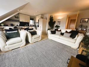 a living room with white couches and a kitchen at Footprints - gorgeous coastal apartment with sea views in Saundersfoot +23 photos