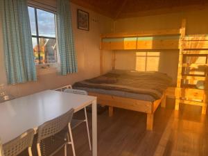 Hooiberghut op boerderij في لايدسخيندام: غرفة نوم مع سرير بطابقين وطاولة وكراسي