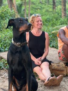a woman is sitting next to a black dog at The Peace Hostel in Arambol