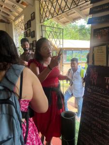 a woman in a red dress taking a picture with her cell phone at The Peace Hostel in Arambol