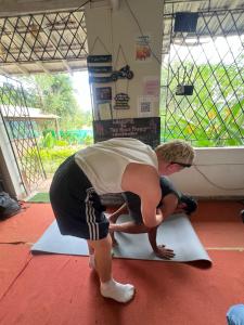 a young boy is bending over on a yoga mat at The Peace Hostel in Arambol