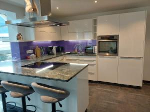 Appartement WiSo في ماوترندورف: مطبخ مع دواليب بيضاء وجزيرة مع كراسي بار