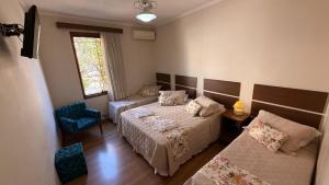 a bedroom with two beds and a couch and a window at Hotel Vitoria Marchi in Serra Negra