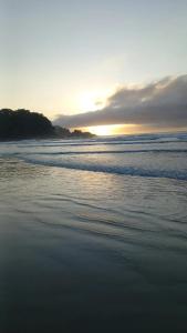 een strand met de zon die ondergaat boven de oceaan bij Rede Bem Te Vi - Itaguá in Ubatuba
