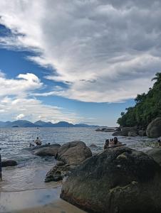 een groep mensen die op rotsen in het water zitten bij Rede Bem Te Vi - Itaguá in Ubatuba