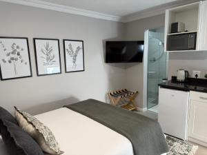 a white bedroom with a bed and a kitchen at Stellenbosch Serenity in Stellenbosch
