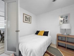 a white bedroom with a bed with a yellow pillow at Tropical Naguabo Beach House Pool n Beach in Naguabo +18 photos