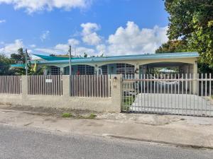 a white fence in front of a house with a blue roof at Tropical Naguabo Beach House Pool n Beach in Naguabo