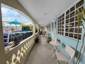 a balcony with chairs and tables and a pool at Tropical Naguabo Beach House Pool n Beach in Naguabo