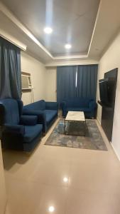 a living room with blue couches and a coffee table at فندق اجنحة السمو إن in Aḩad al Masāriḩah